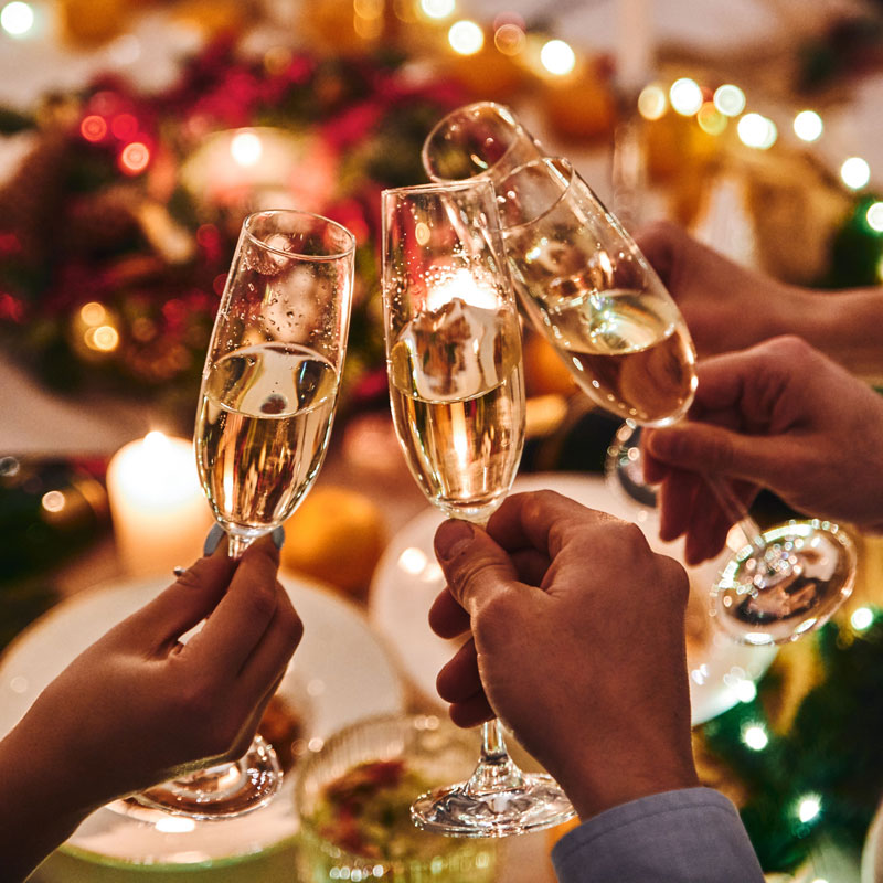 Hænder med champagneglas, som skåler nytåret ind - begiveheder hos Dinesens